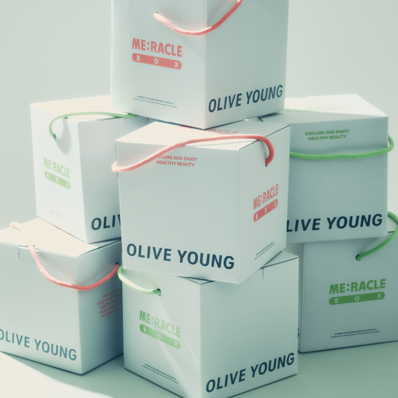 Stacked pastel boxes with colored handles are labeled “OLIVE YOUNG” and “ME:RACLE.”