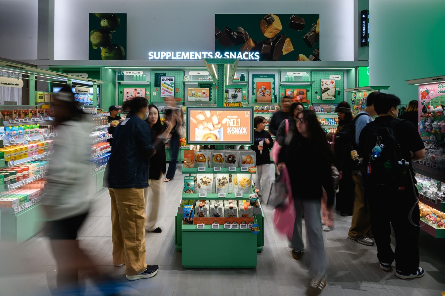 Shoppers browse supplements and snacks in a brightly lit store.