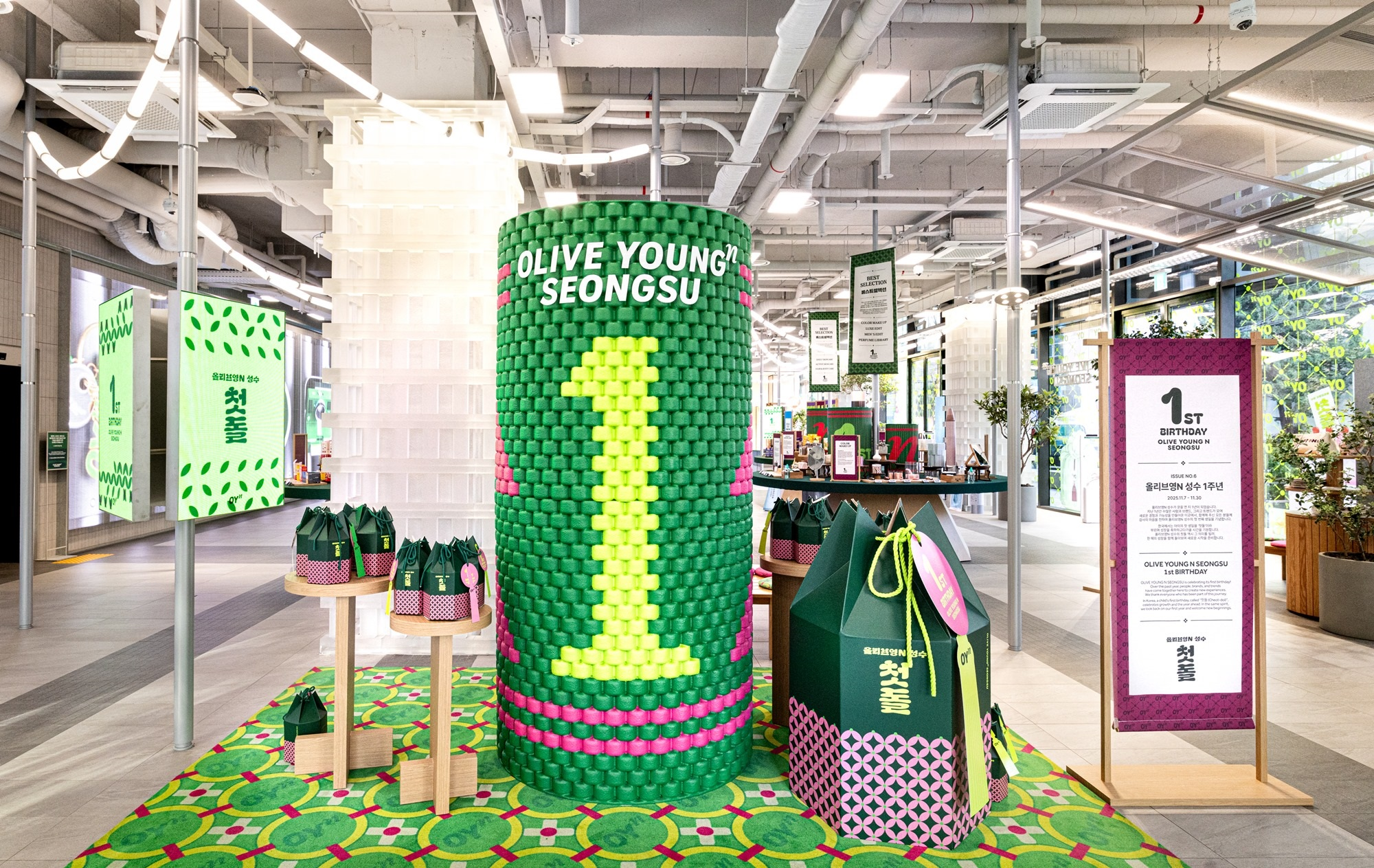 A colorful Olive Young Seongsu display features a green cylinder, gift bags, and birthday signage.