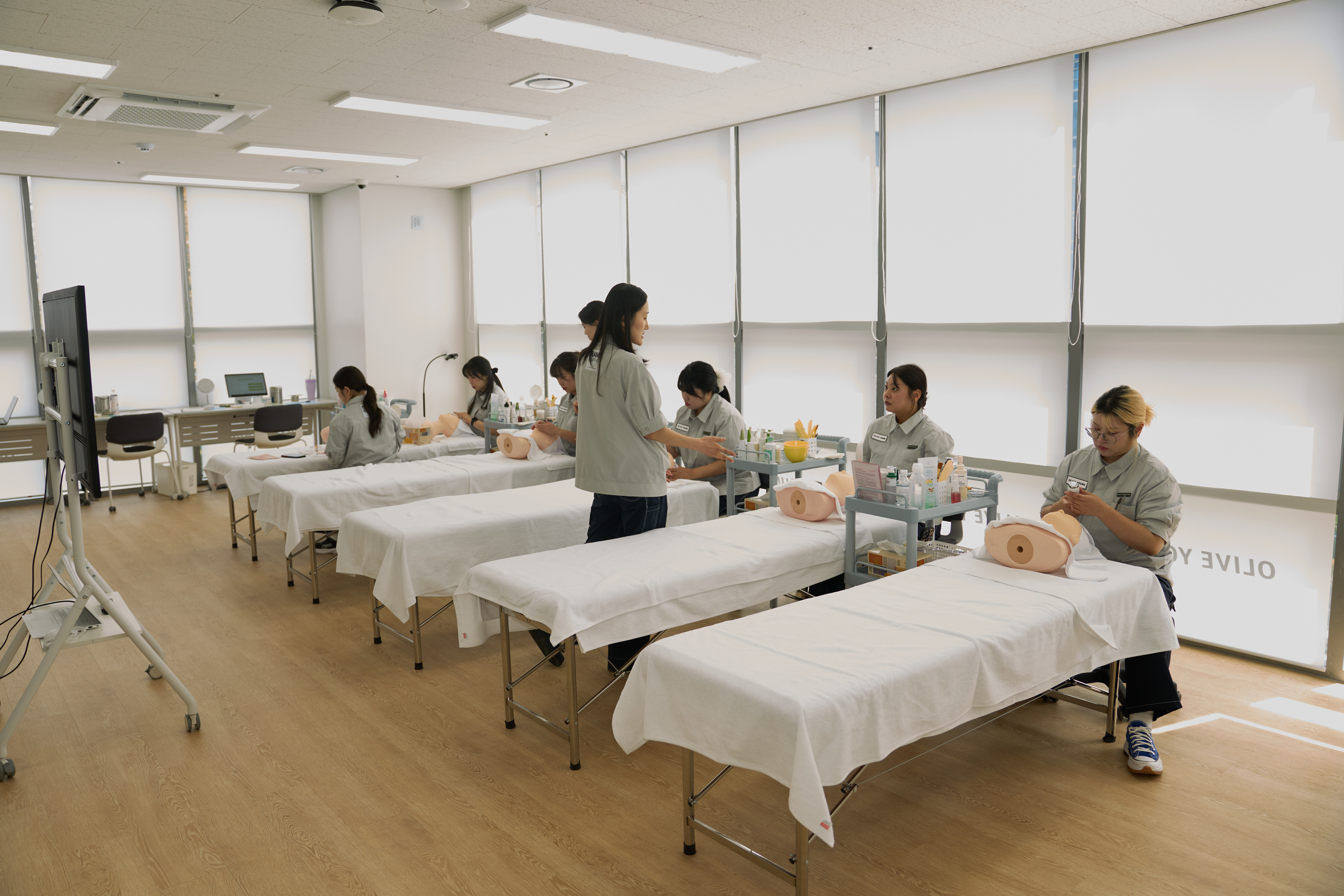 Beauty consultants practice skincare skills on mannequins in a classroom.