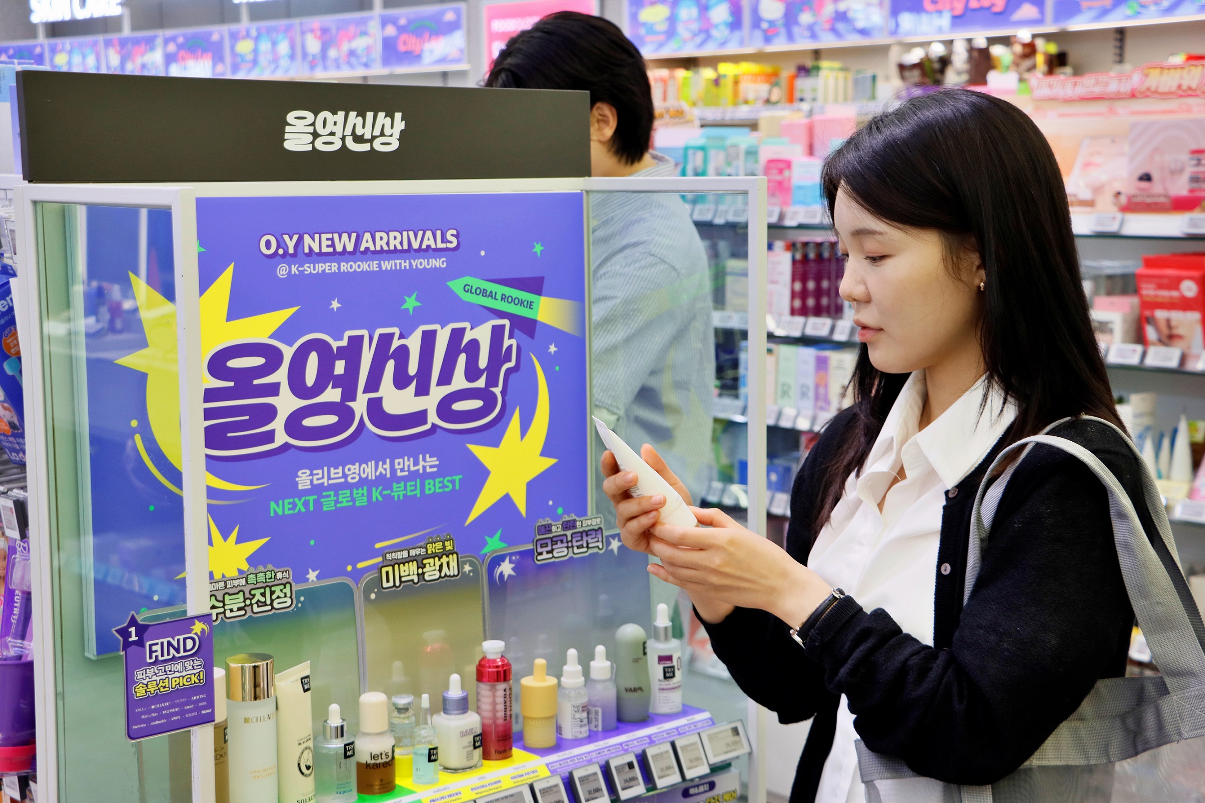 화장품 매장에서 한 여성이 제품을 들고 ‘올영신상’ 진열대 앞에서 살펴보고 있다.