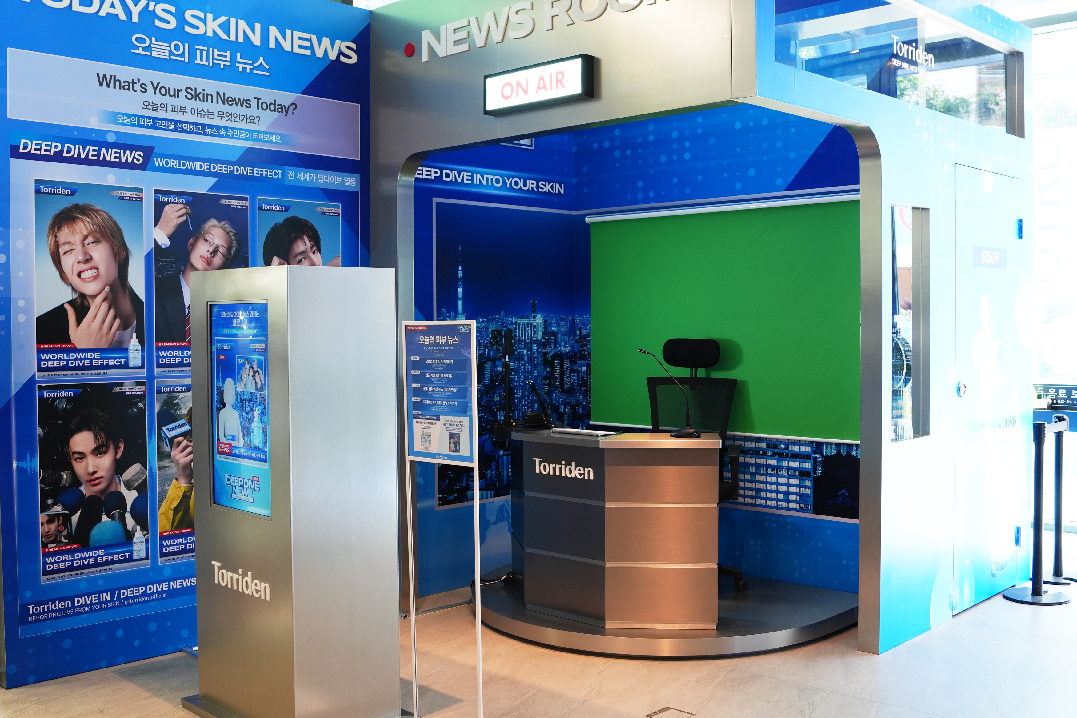 An empty Torriden news set has a desk, green screen, posters and an ON AIR sign.