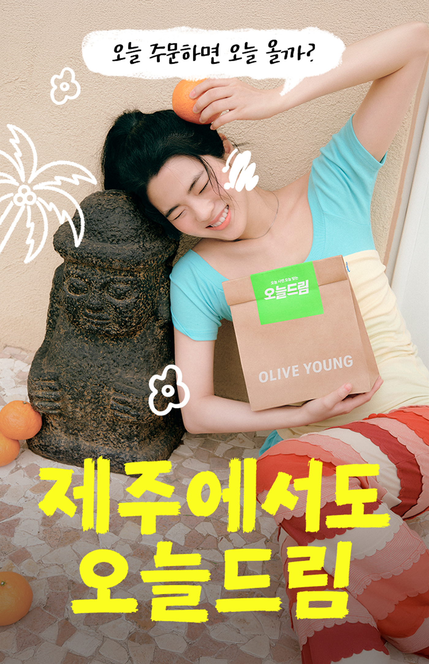 A smiling woman holds an Olive Young shopping bag beside a stone sculpture and oranges.