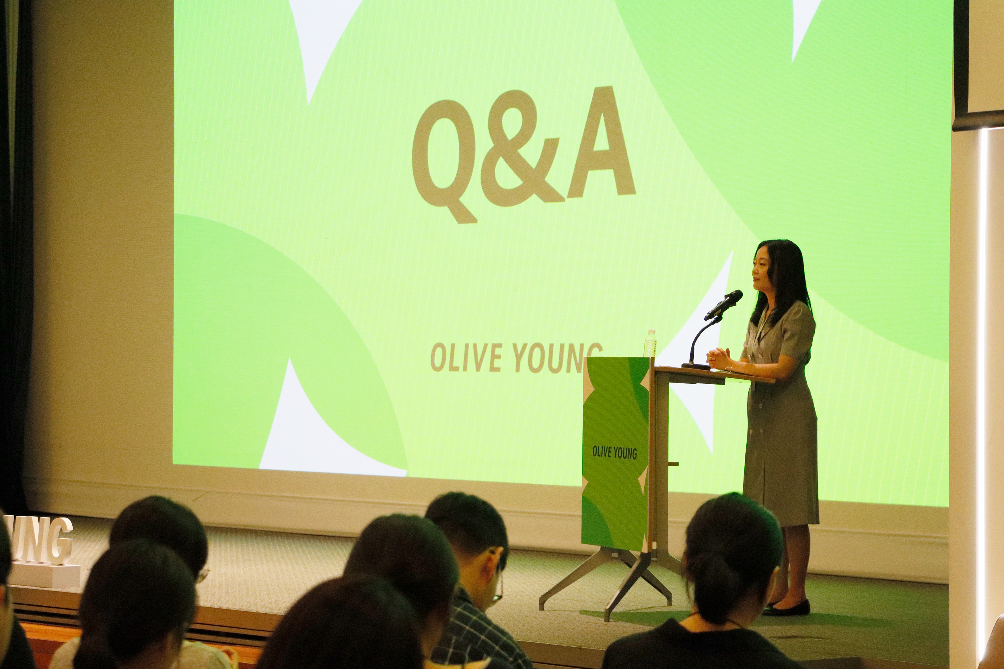 A women standing on stage in front of a screen that reads "Q&A"