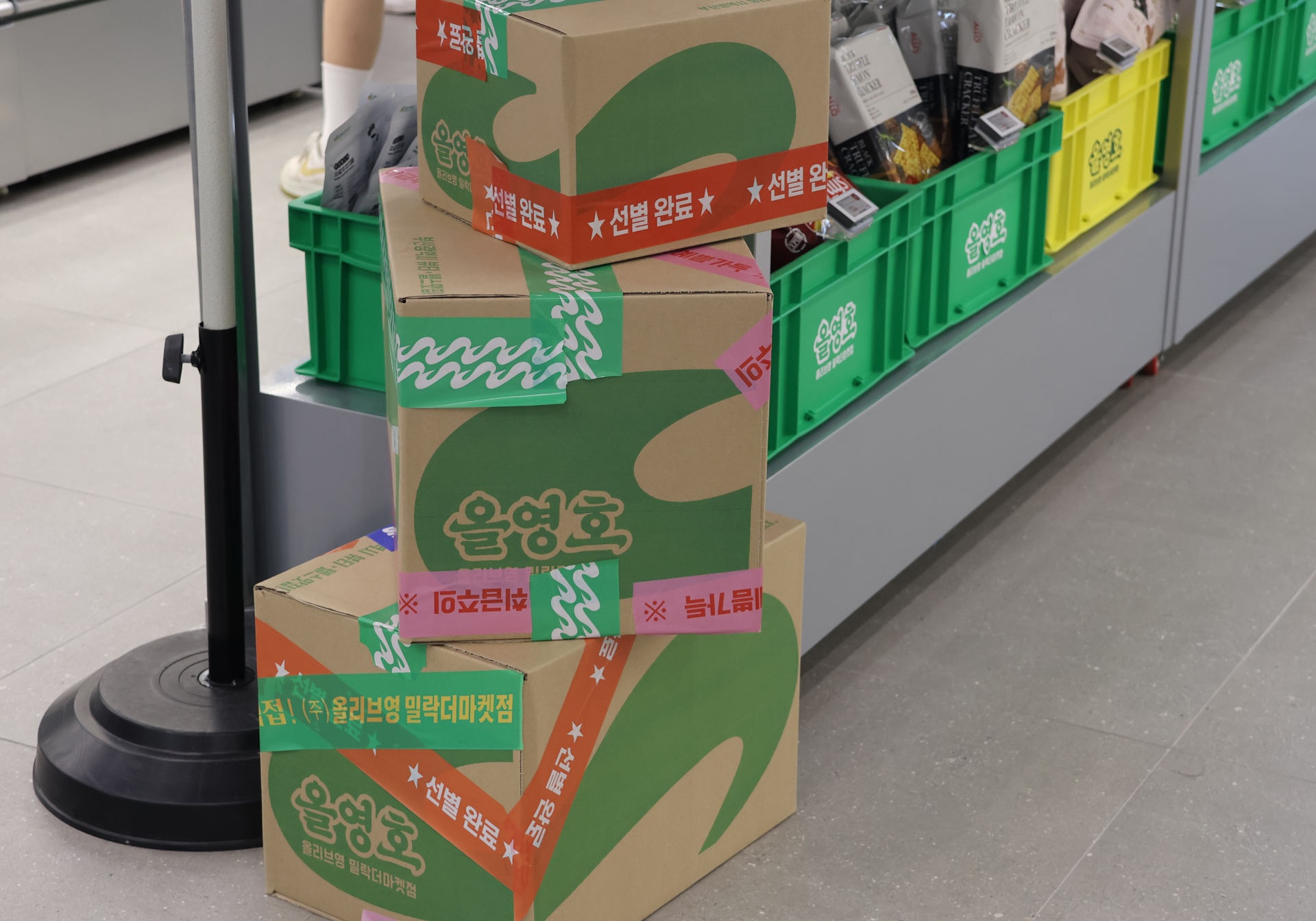 매장 통로에 ‘선별 완료’ 테이프가 붙은 상자와 초록색 운반 상자가 놓여 있다.