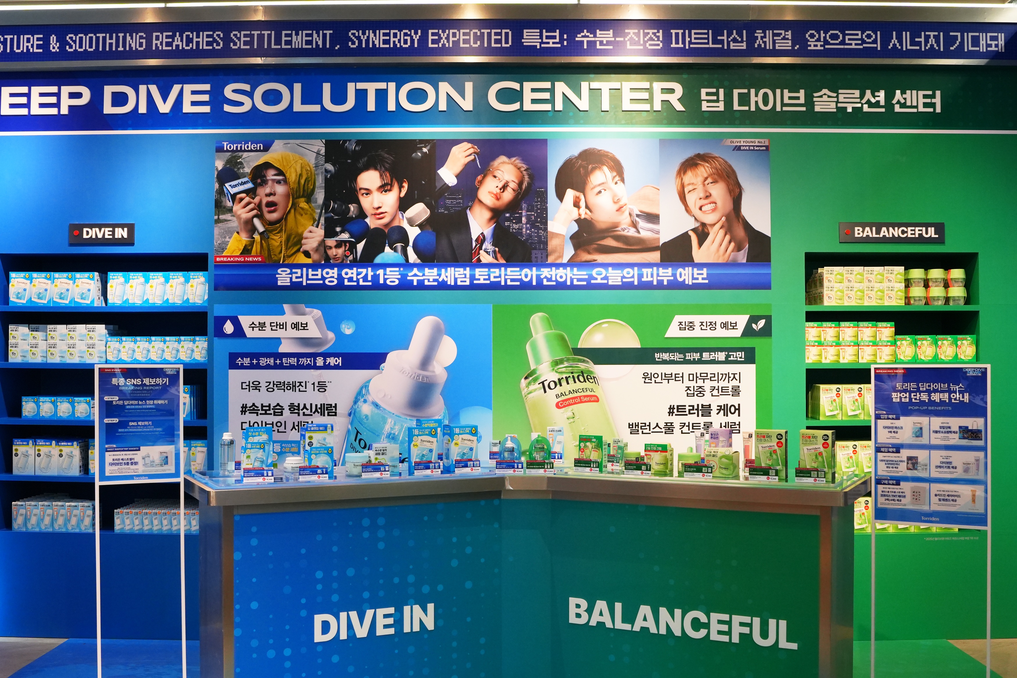 A Torriden skincare display features shelves of products and colorful posters of four models.