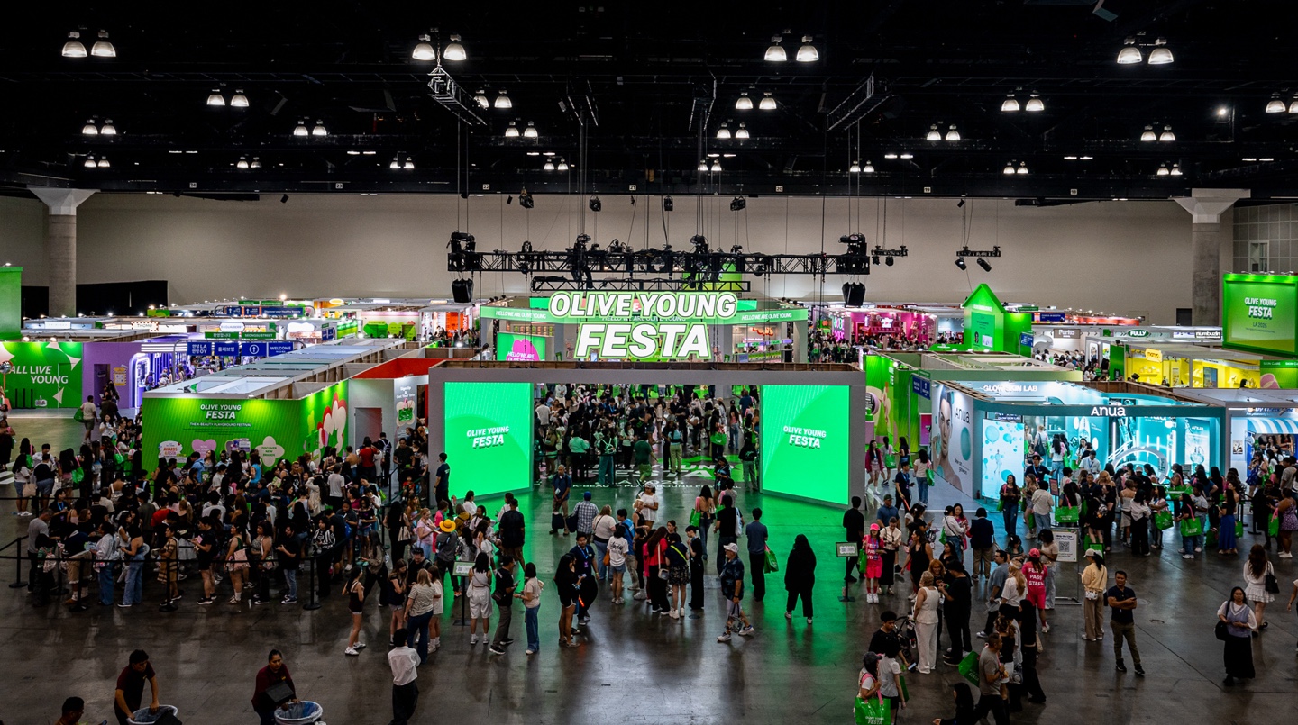 A crowded convention hall features booths and a large Olive Young Festa entrance.