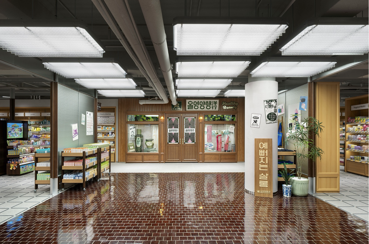 A brightly lit store interior with shelves of products and a central Korean beauty shop.